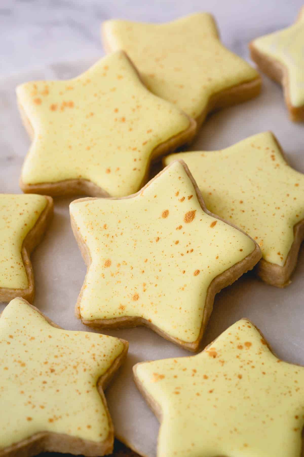 Star shaped sugar cookies frosted with yellow royal icing and gold speckles.