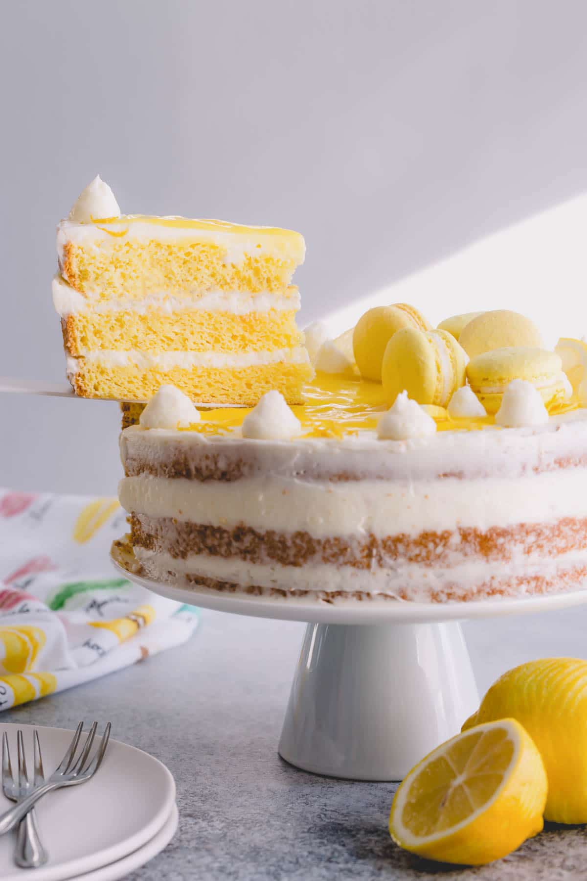 Lemon layer cake on a cake stand with one slice lifted.