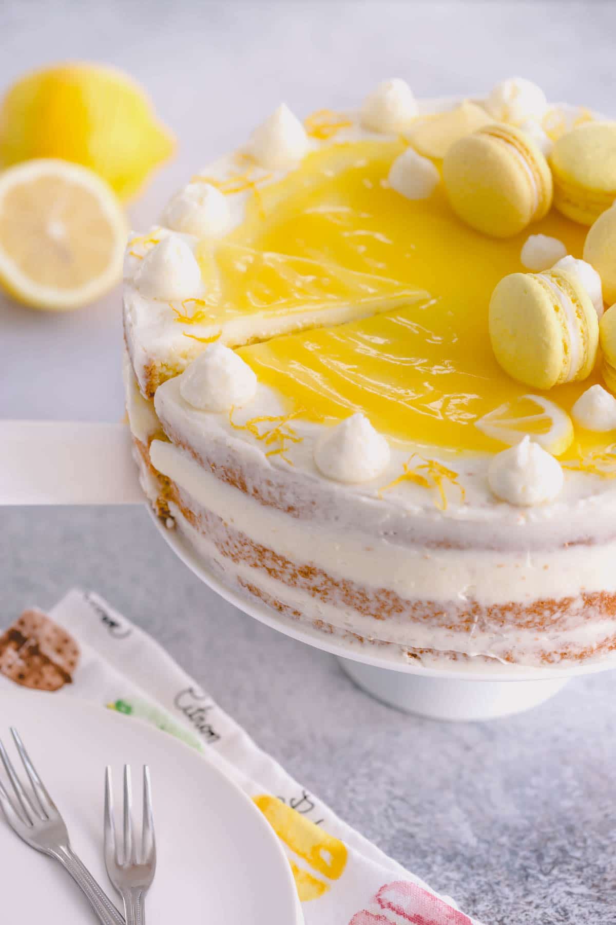 Lemon layer cake on a cake stand and topped with lemon macarons.