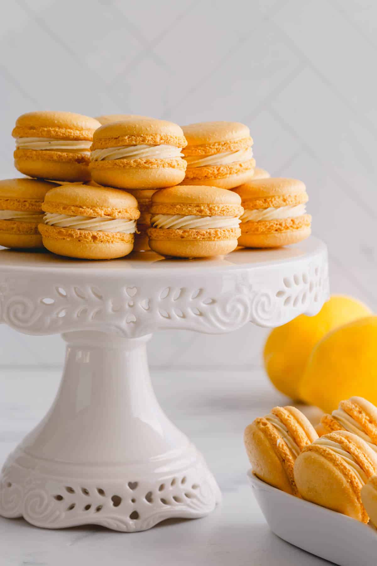 Assembled lemon macarons stacked on a cake platter.