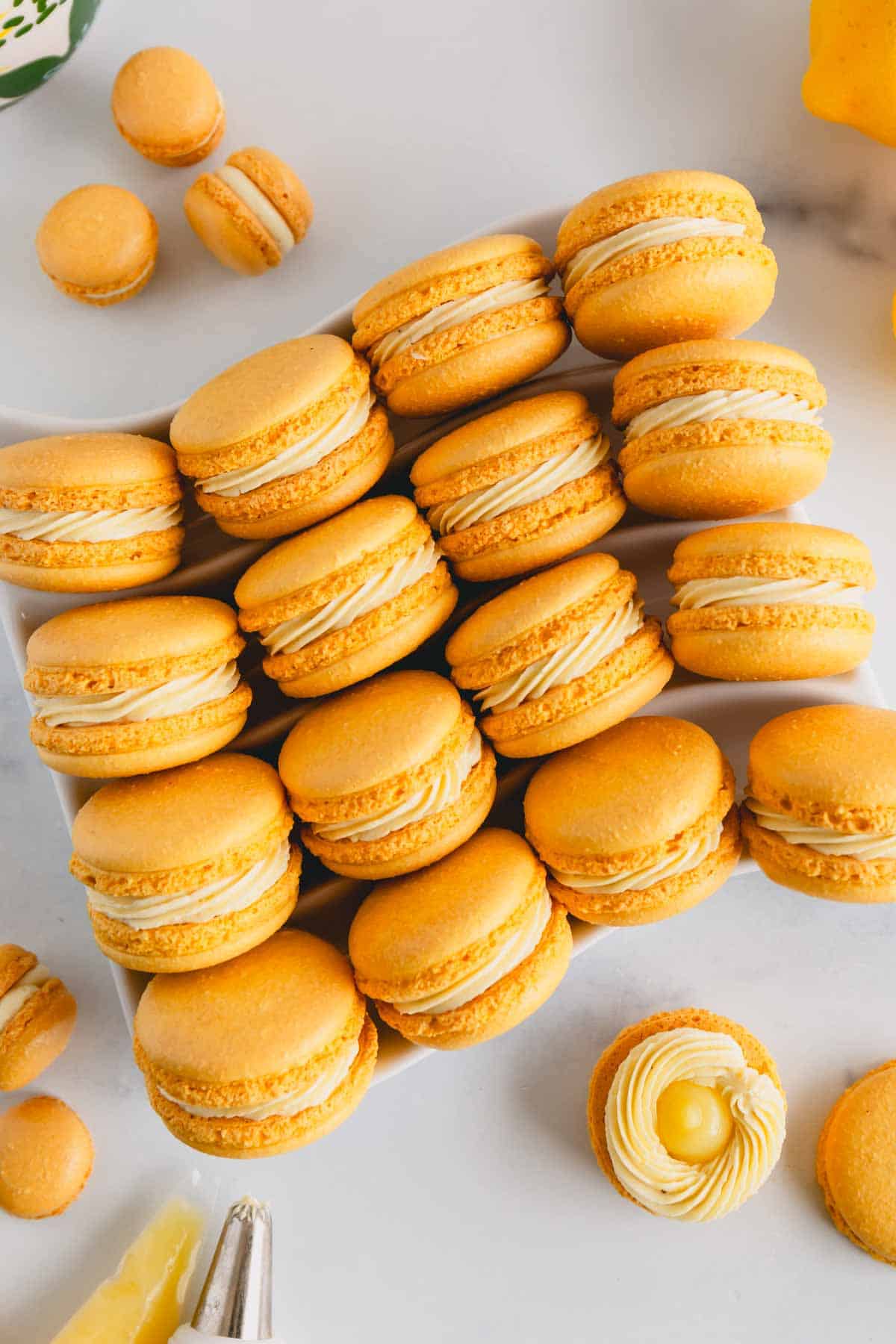 Lemon curd and buttercream filled yellow macarons on a serving platter.