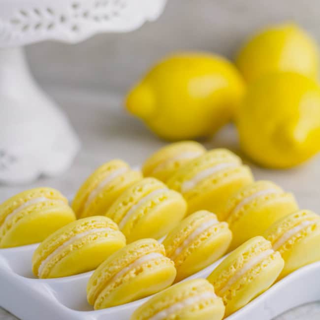 Lemon macarons arranged on a white serving platter.
