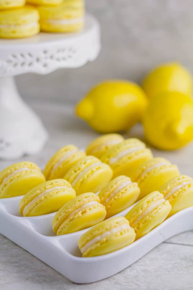 Lemon macarons arranged on a white serving platter.