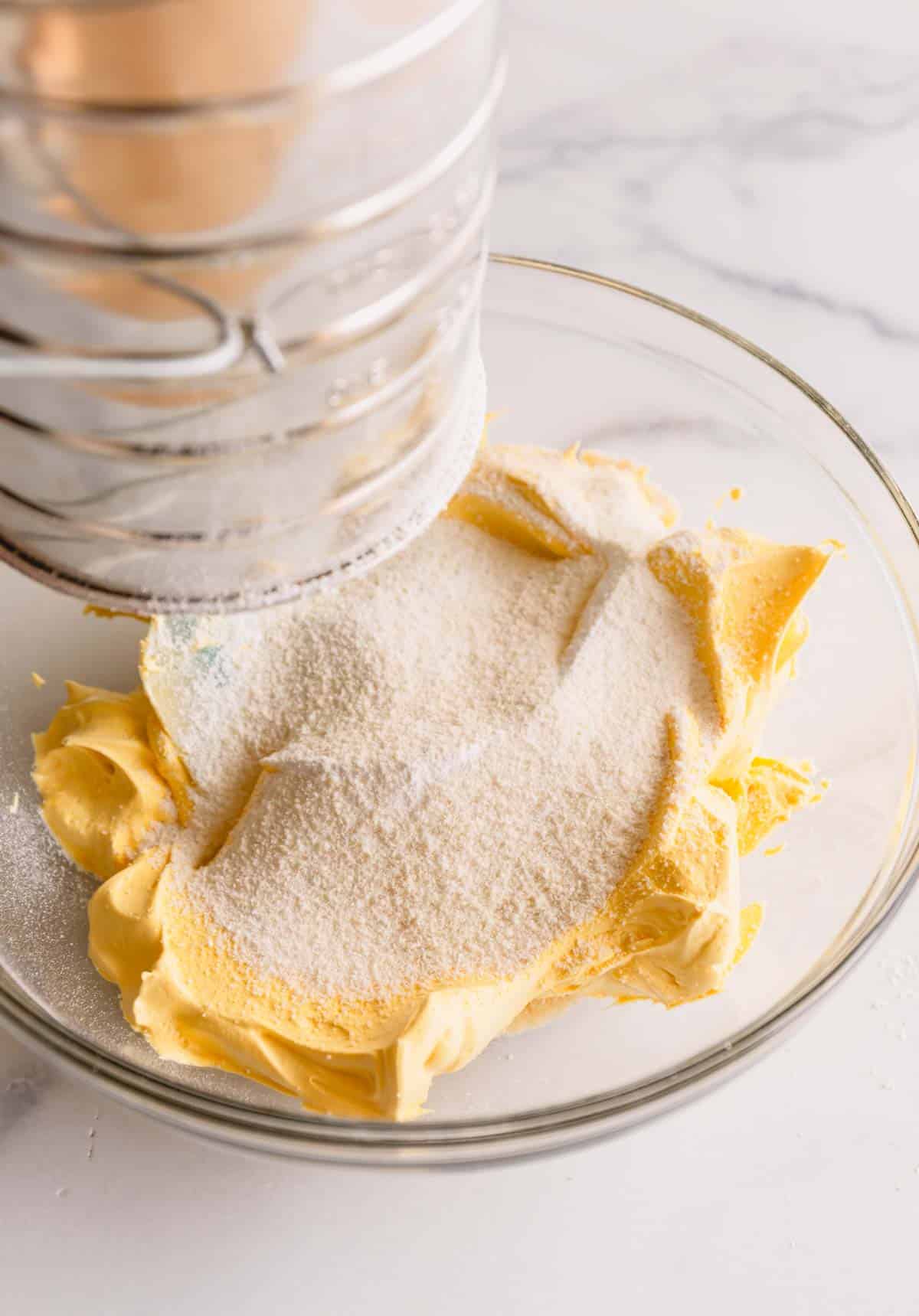 dry ingredients being sifted into the yellow meringue.