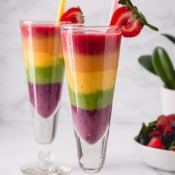 2 tall glasses of rainbow smoothies.