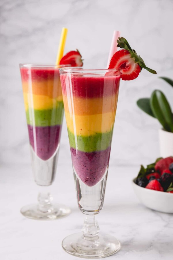 2 tall glasses of rainbow smoothies.
