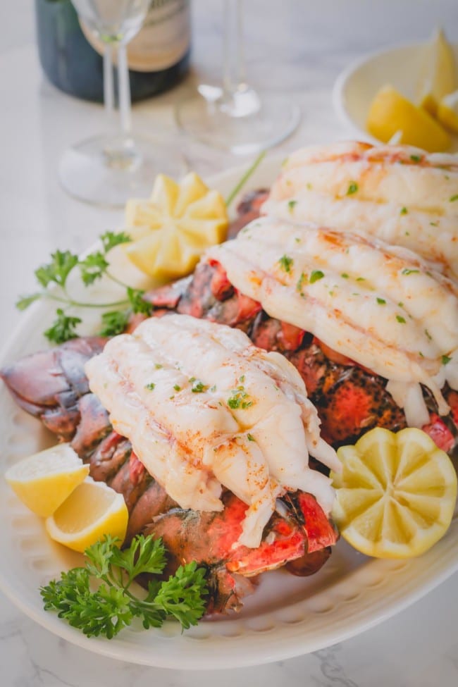 cooked lobster tails on plate with lemons