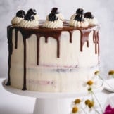 Black Forest cake with chocolate drizzle on a white cake platter.