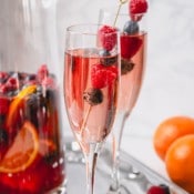Moscato sangria in a champagne glass garnished with raspberries and blueberries.