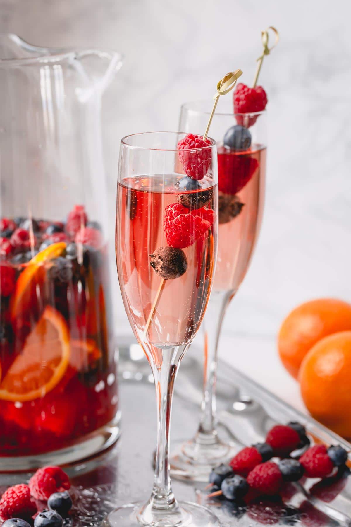 Moscato sangria in a champagne glass garnished with raspberries and blueberries.
