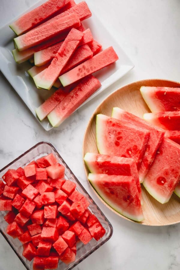 Three plates of watermelon wedges, sticks and cubes.