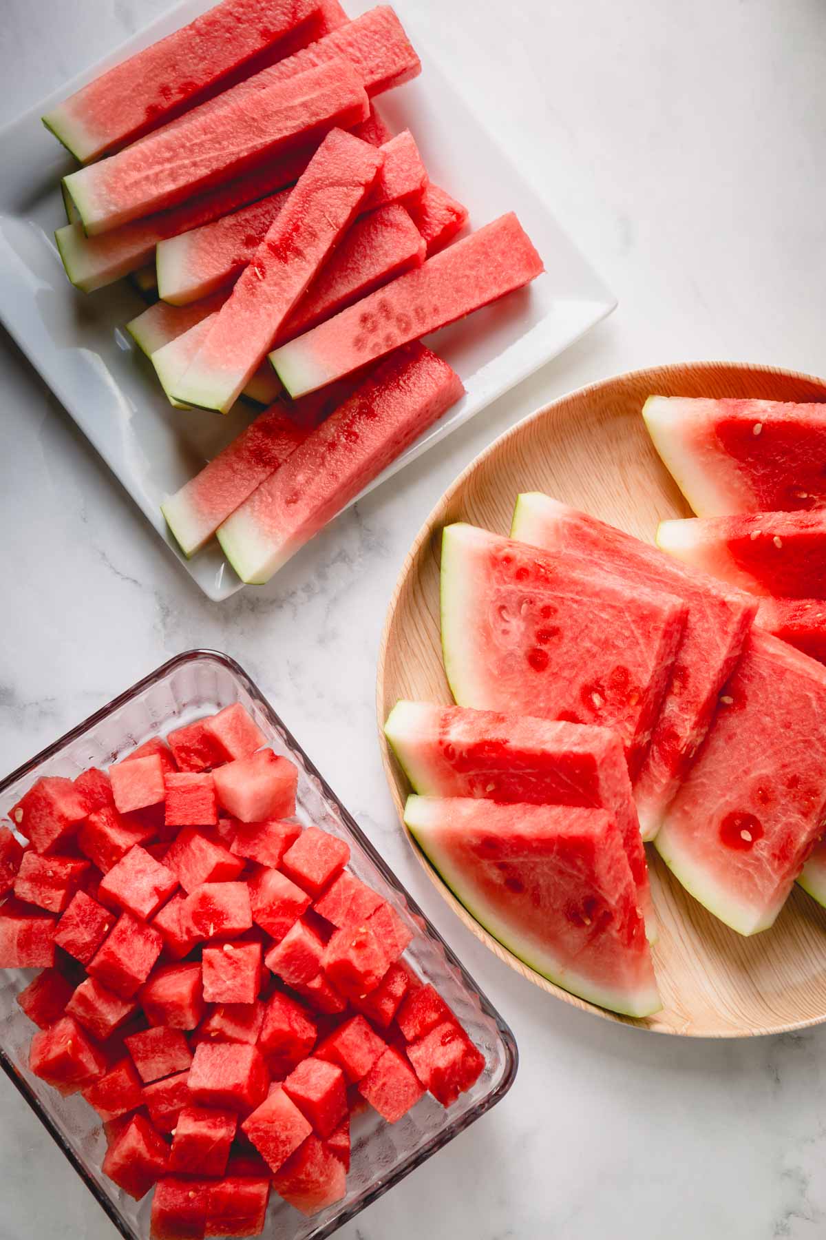 Three plates of watermelon wedges, sticks and cubes.