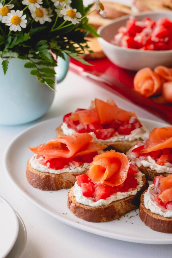 Assembled smoked salmon crostini on a white serving platter.