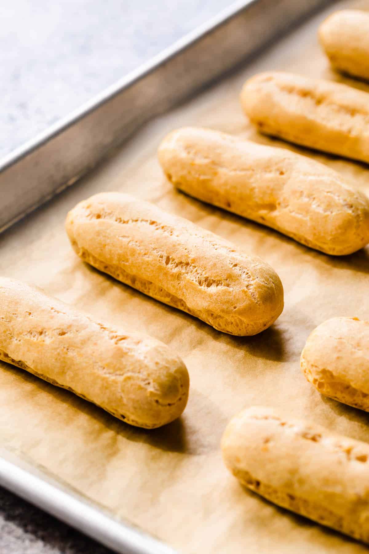 Baked eclair shells on a baking sheet lined with parchment paper.