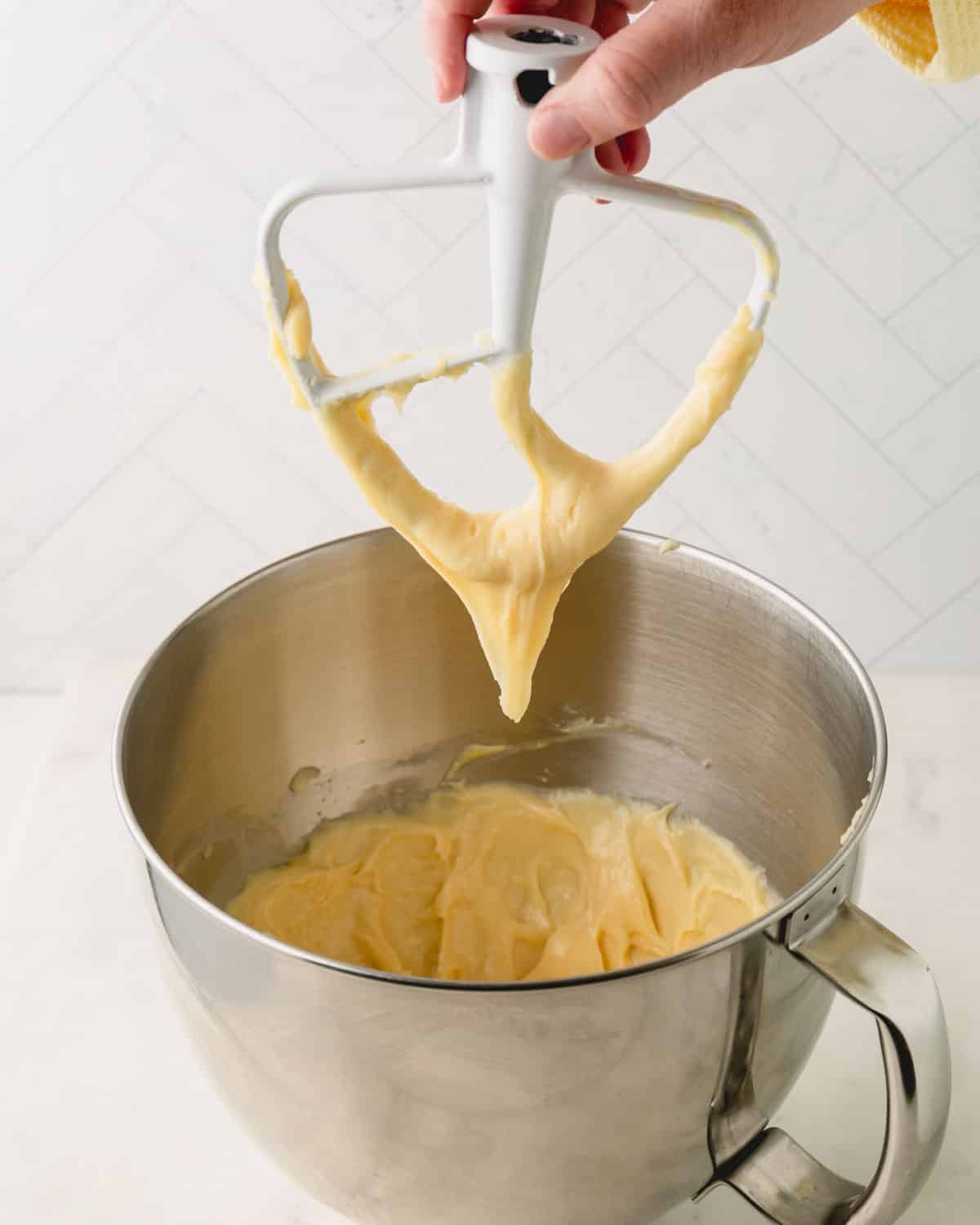 Paddle attachment is lifted from the bowl of choux pastry dough formed a V-shape on the attachment.