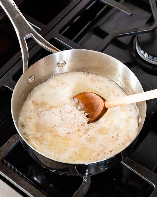 Dough is dumped into the liquid in a stainless steel saucepan.