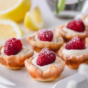 Raspberry lemon tartlets arranged on a rectangular serving platter.