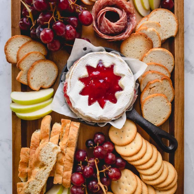 Cheese board with a raspberry baked brie in the middle.