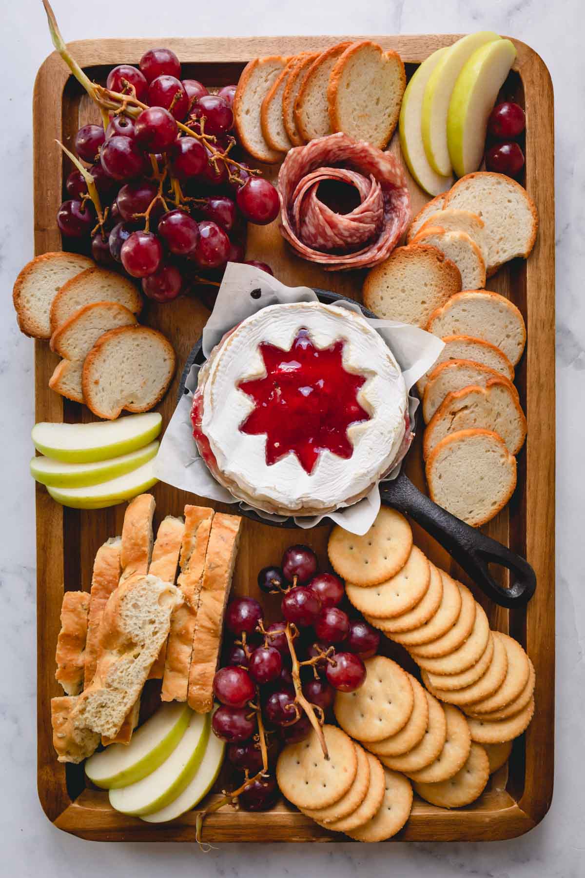 Cheese board with a raspberry baked brie in the middle.