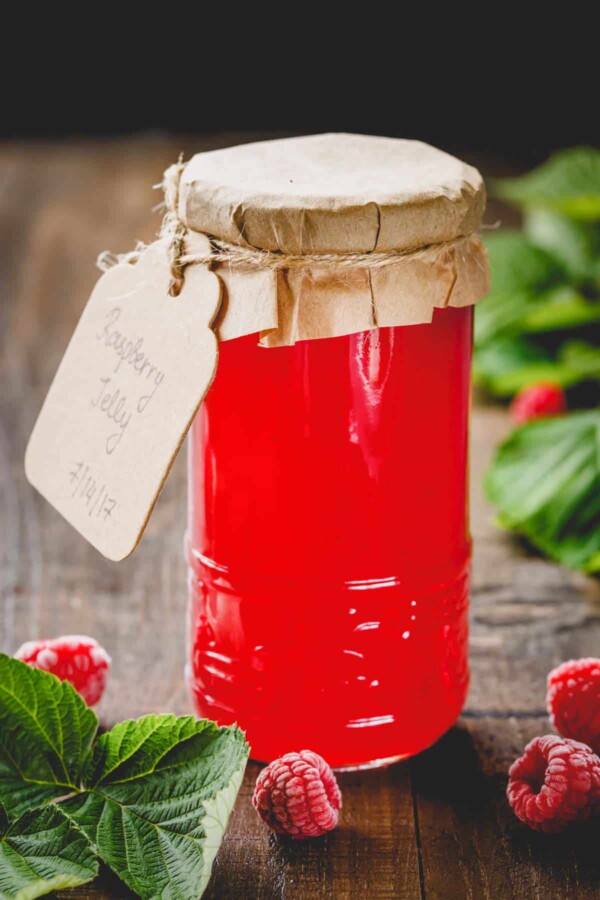 A talk glass jar of seedless raspberry jam.
