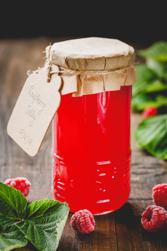 A talk glass jar of seedless raspberry jam.