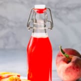 Peach syrup in a tall glass bottle.