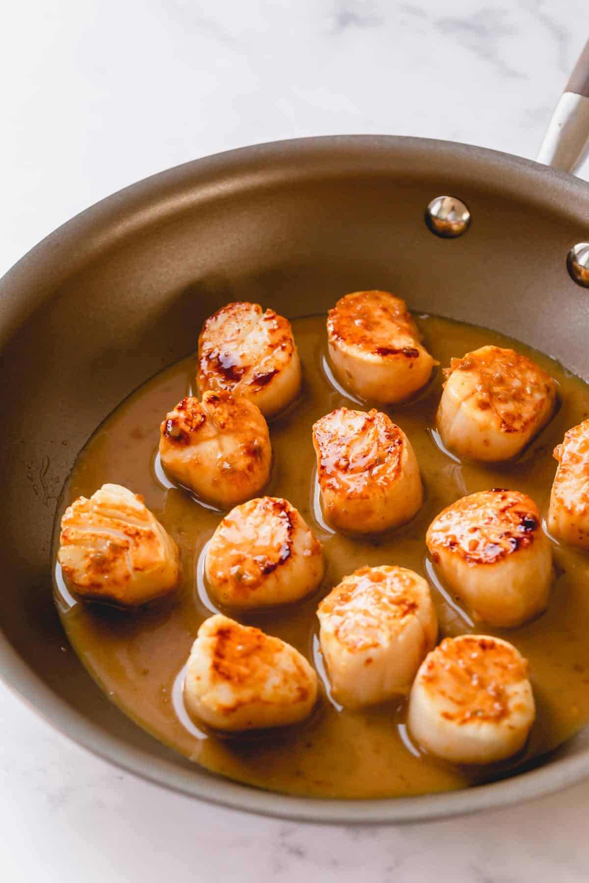 Seared scallops with tequila lime sauce in a skillet.