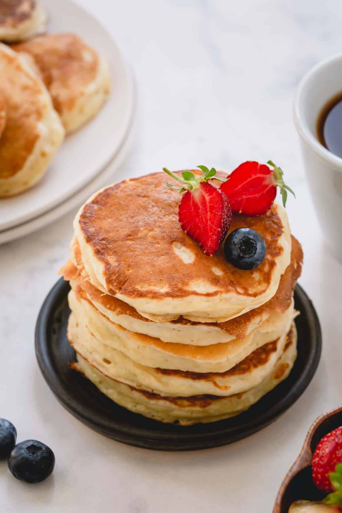 a stack of buttermilk pancakes with fruit.
