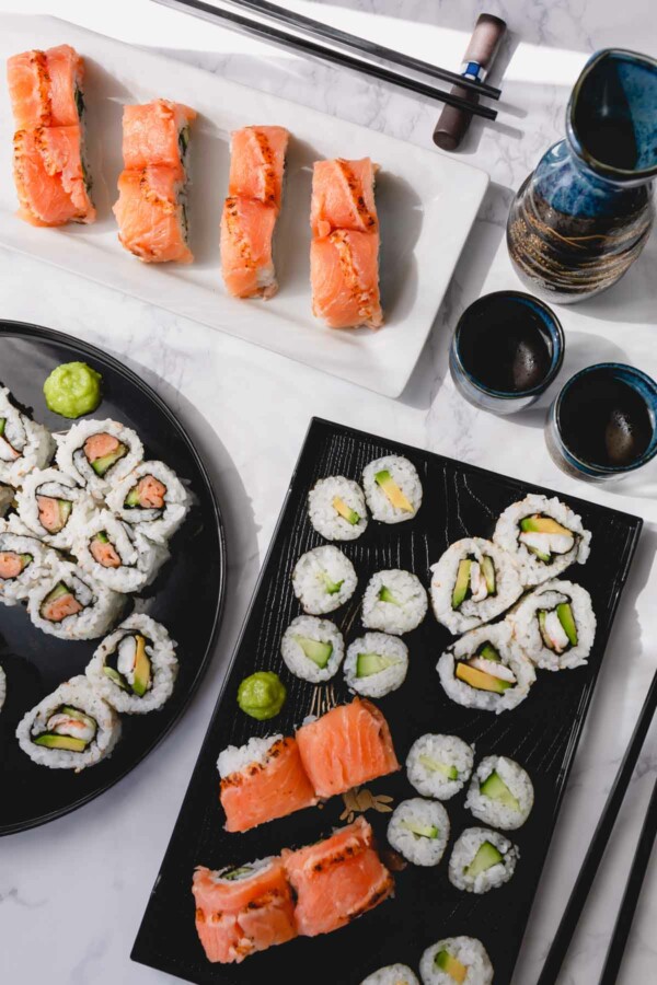 Various homemade sushi rolls on multiple platters.