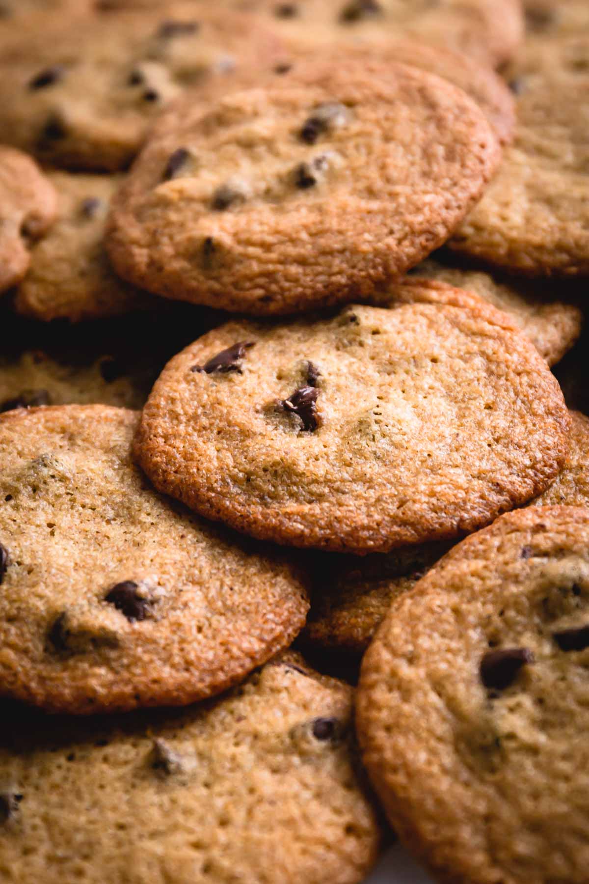 thin chocolate chip cookies in a pile.