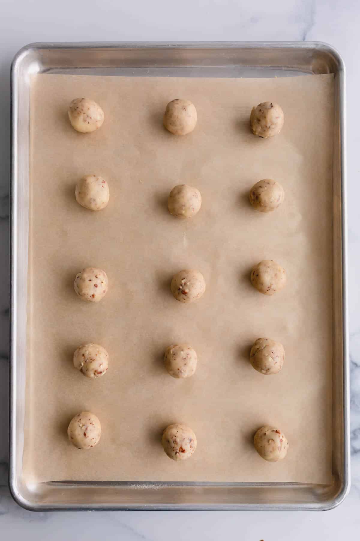 Snowball cookie balls arranged on a baking sheet.