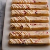 orange cranberry shortbread cookie sticks on cutting board.