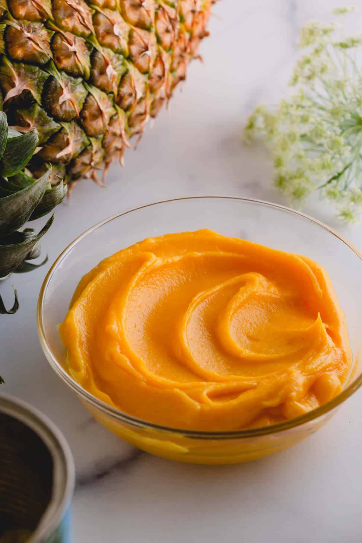 Thick pineapple curd in a glass bowl.