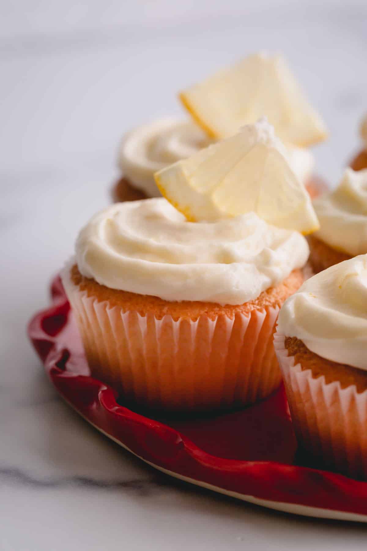 lemon cupcakes with cream cheese frosting on a platter.