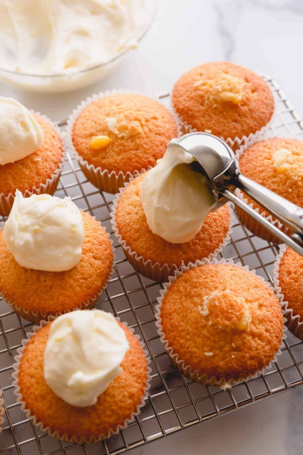 scooping frosting onto lemon cupcakes.