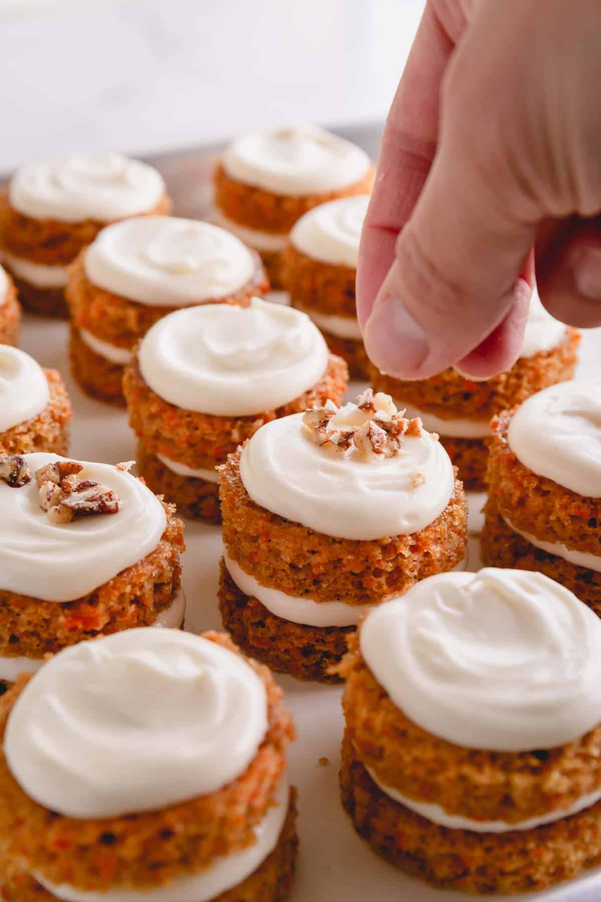 sprinkling candied pecans on mini carrot cakes. 