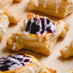 Baked cherry cheese danishes on a parchment paper-lined baking sheet.