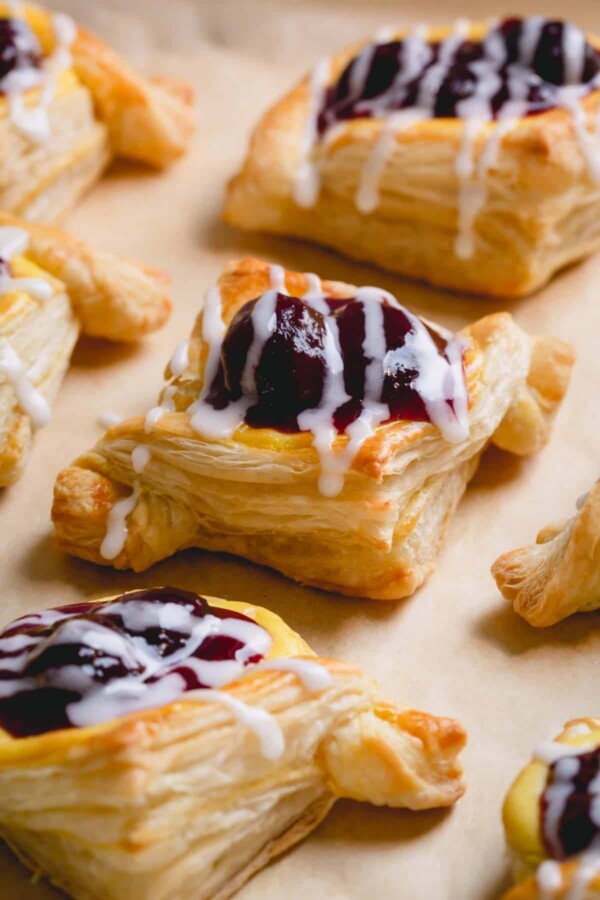 Baked cherry cheese danishes on a parchment paper-lined baking sheet.