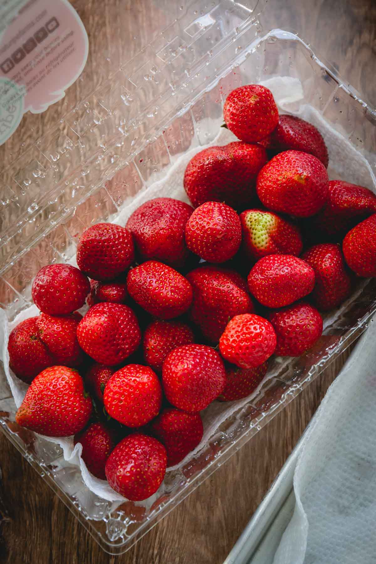 A paper towel-lined clamshell container of fresh strawberries.