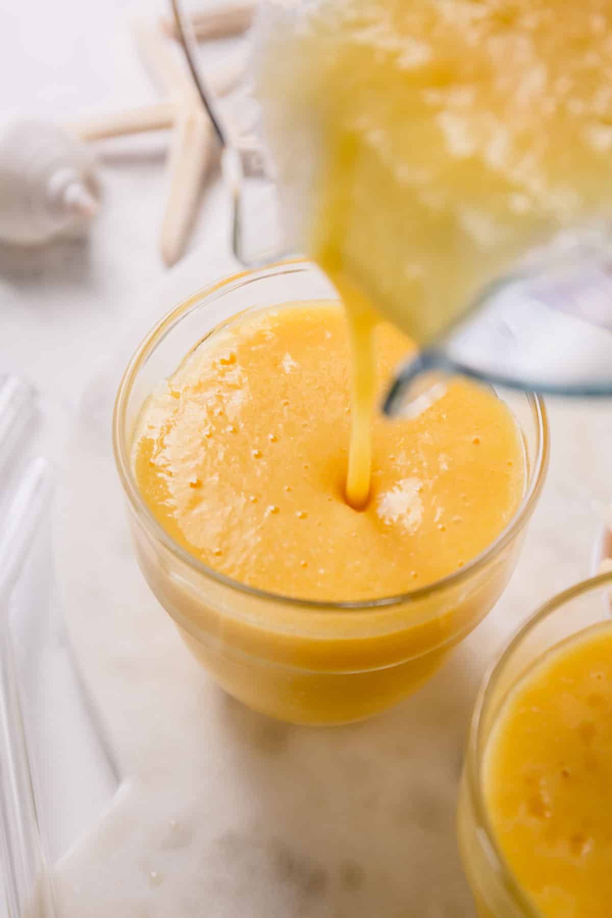 pouring a pineapple orange smoothie into a glass. 