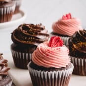 Chocolate cupcakes with some topped with strawberry frosting and others topped with chocolate frosting.
