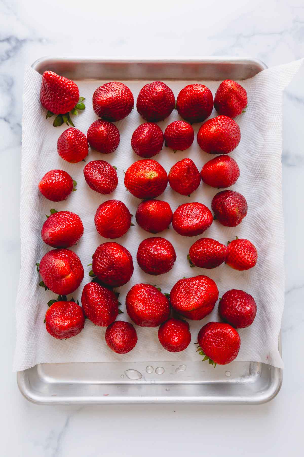 Clean strawberries on top of a paper towel-lined baking sheet.