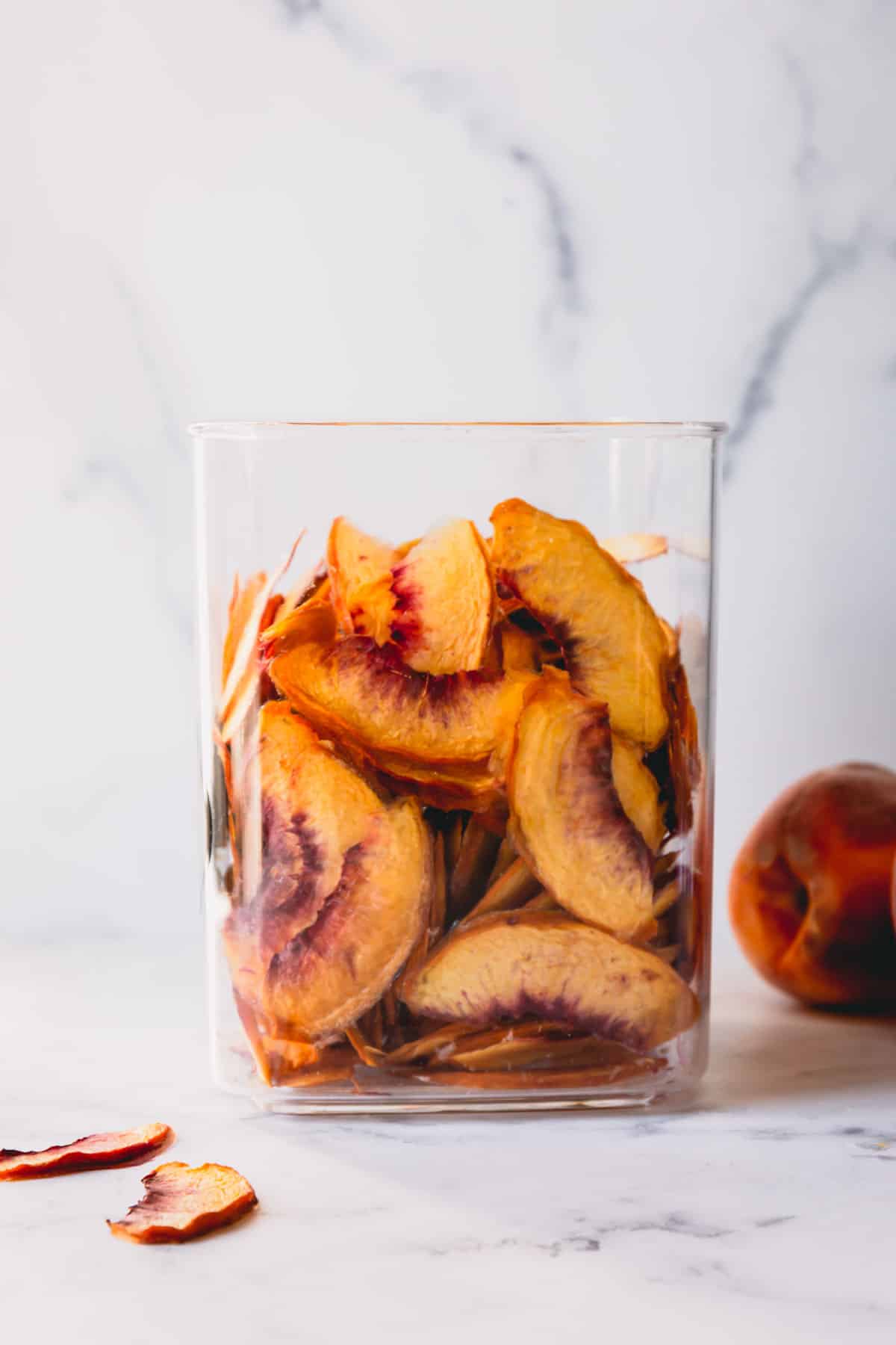 A glass jar of dehydrated peach pieces.