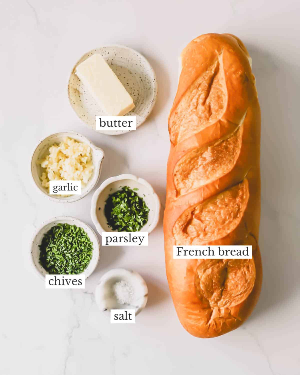 Ingredients needed to make homemade garlic bread with an herbed butter spread.