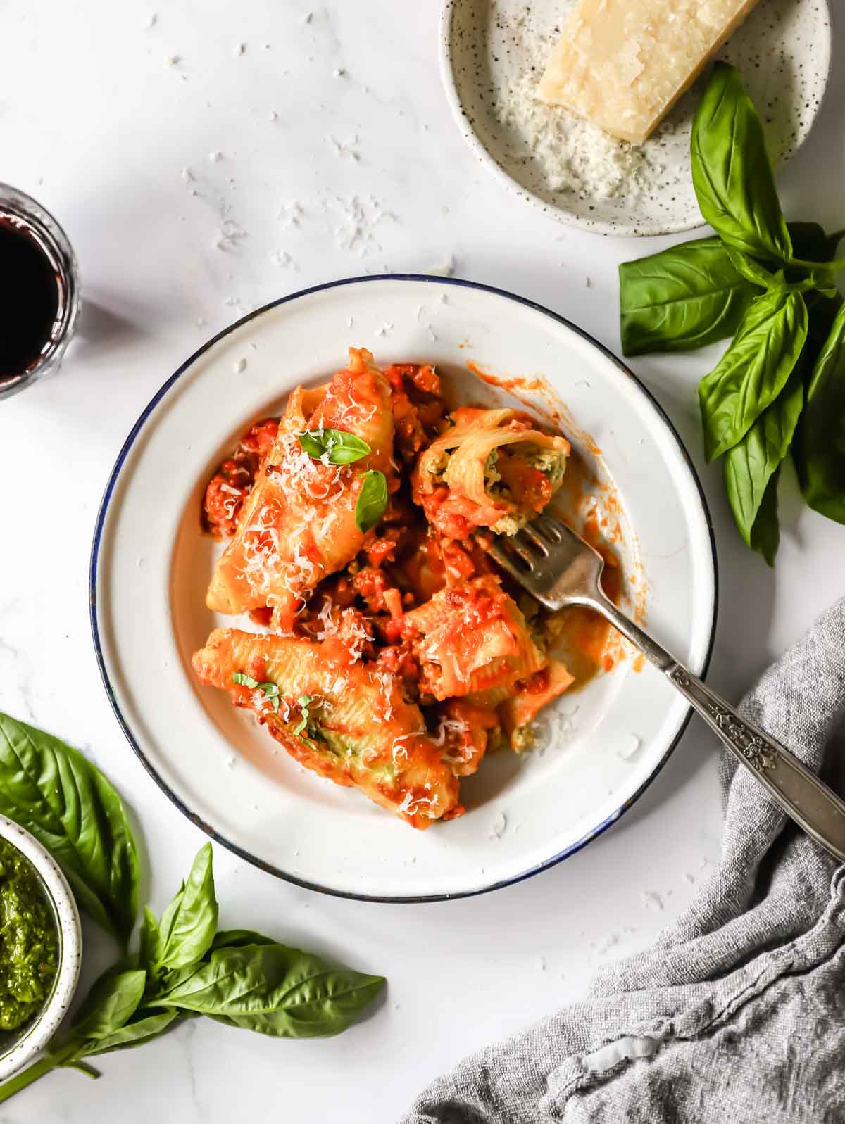 A plate full of pesto ricotta stuffed pasta shells with a fork holding one.