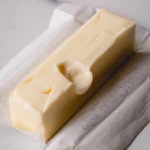 A stick of unwrapped butter with a finger dent in the middle.