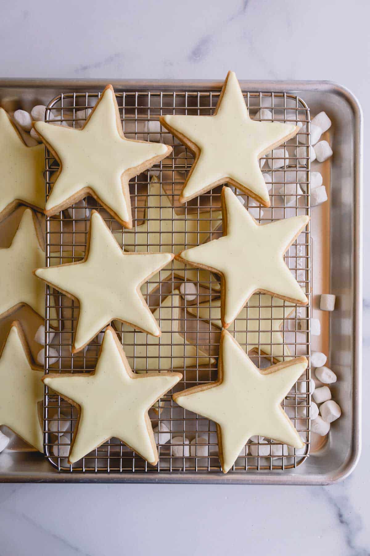 Yellow iced star cookies on a wire rack.