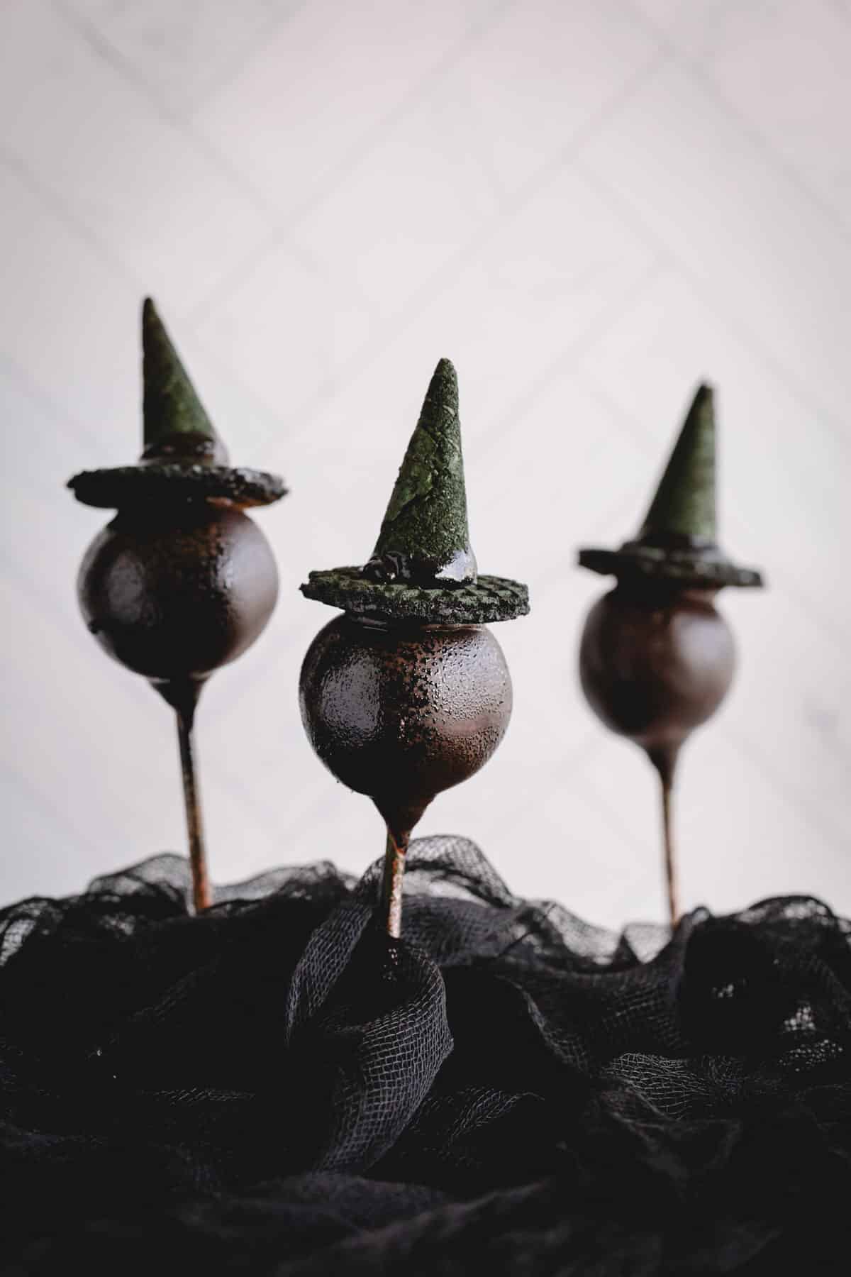 Three chocolate cake pops with witch hats.