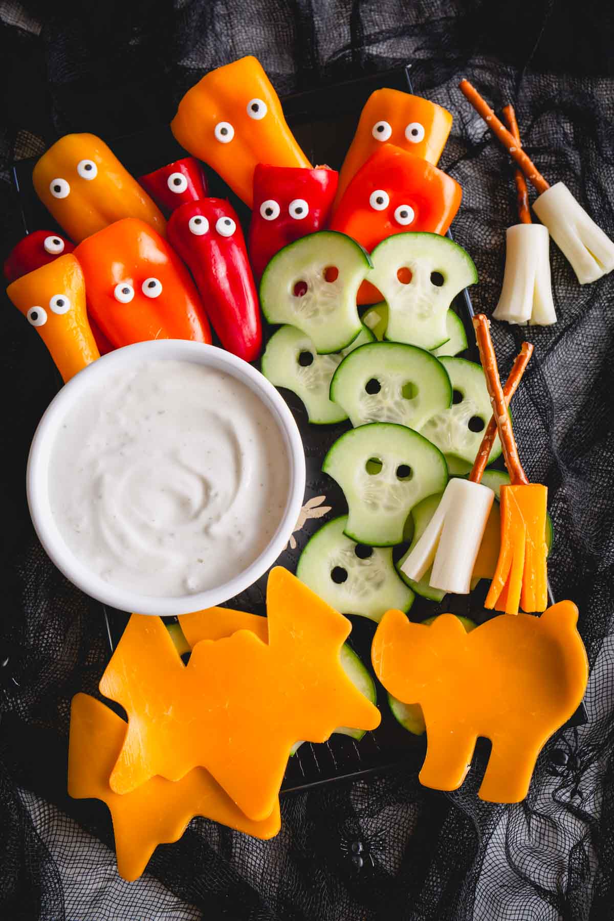 Ghost bell peppers, mummy cucumbers, cheese broomsticks, and cheese shapes with dip.
