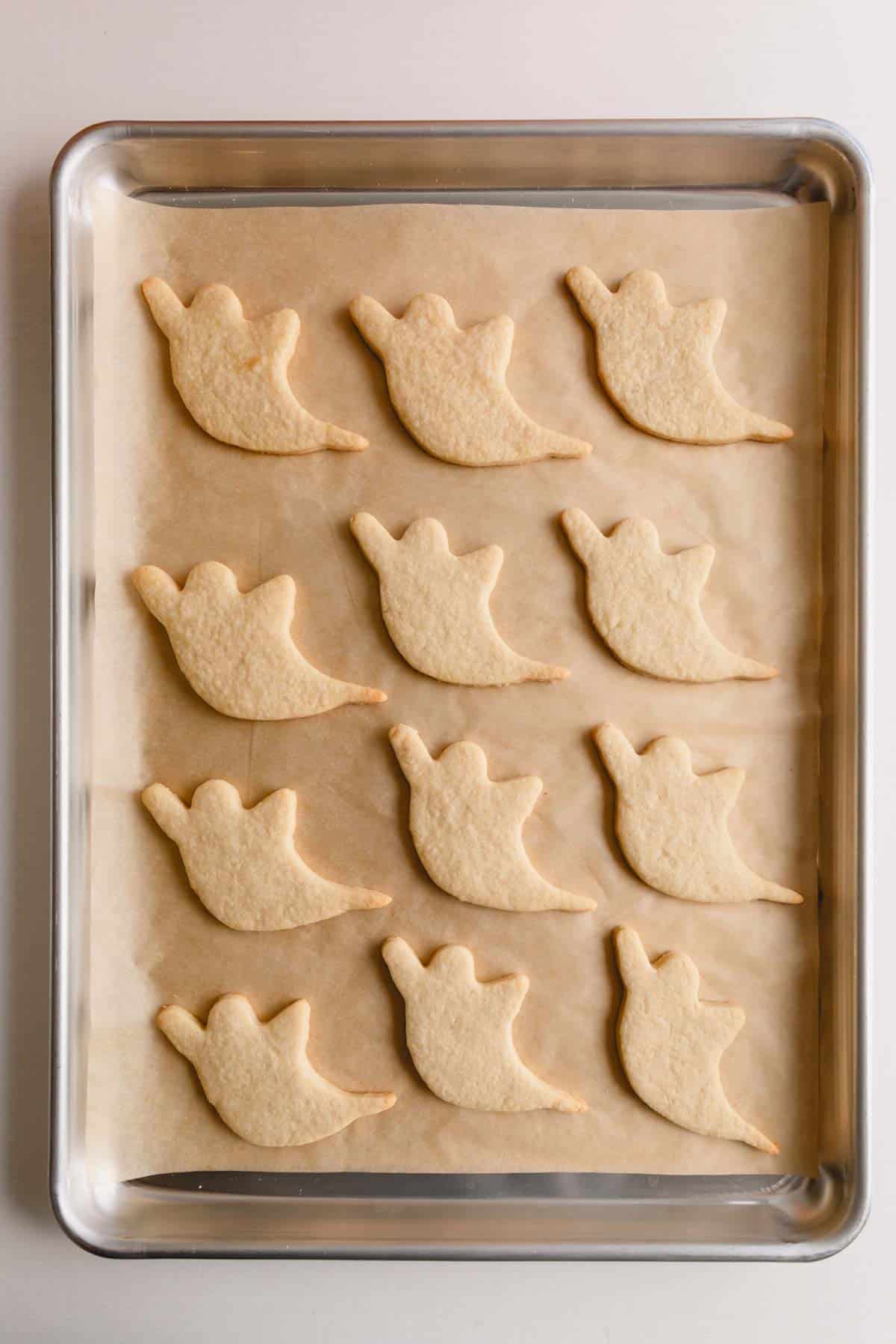 Baked ghost cutout cookies on a baking sheet.